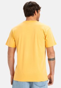 Yellow cotton T-shirt with short sleeves and a crew neck. Features a smooth texture and casual fit, with a plain back view.