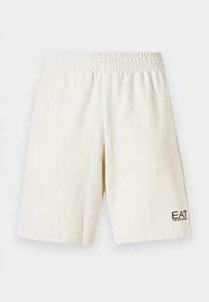 Calções de algodão bege claro com cintura elástica, apresentando um pequeno logo preto da EA7 no canto inferior esquerdo. Design casual e corte reto.