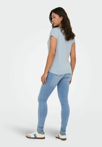 Camiseta de rayas azul claro con mangas cortas, combinada con vaqueros ajustados azul claro y zapatillas blancas con rayas azules.