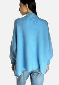 Maglione lavorato a maglia di colore azzurro chiaro, con una vestibilità rilassata, spalle scese e dettagli a coste sul collo e sui polsini, con un'orlo posteriore più lungo.