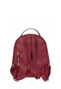 Sac à dos en cuir rouge à texture granuleuse, avec des bretelles réglables, une poignée sur le dessus et un détail de fermeture éclair dorée sur un côté. Texture lisse et forme arrondie.