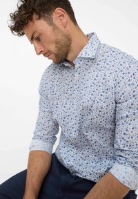 Camicia a fiori blu chiaro con accenti blu scuro, design con colletto e chiusura a bottoni; tessuto testurizzato con maniche arrotolate.