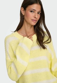 Strickpullover mit einem hellgelben und weißen gestreiften Muster, lässiger Schnitt, überschnittenen Schultern sowie Rippbündchen am Kragen und an den Ärmeln.