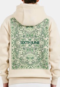 Sudadera beige con un gran diseño de paisley verde en la espalda, con el texto "SIXTH JUNE" en letras verdes en negrita y en contraste.