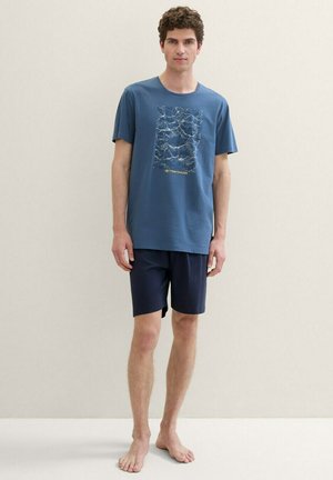 Blaues Baumwoll-T-Shirt mit Wellenmuster und Logo, kombiniert mit navyblauen Shorts. Mit lässiger Passform und kurzen Ärmeln.