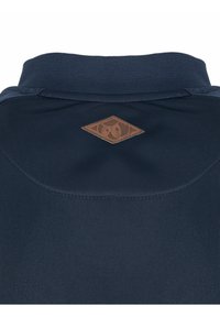 Polo-shirt bleu marine avec un tissu texturé, doté d'un patch en cuir marron en forme de losange sur le col arrière.