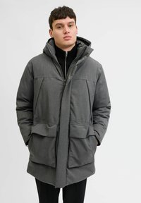 Pelēks polsterēts mēteli ar kapuci, divām lielām priekšējām kabatām un ar rāvējslēdzēju. Gluda, teksturēta auduma un brīvā piegriezuma dizains.