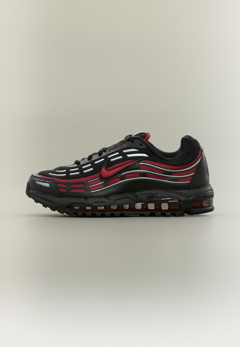 Chaussure de sport noire avec accents rouges, tige en mesh et design distinctif en forme d'onde. Équipée d'un amorti Air et d'une semelle extérieure texturée pour une meilleure adhérence.