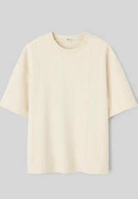 T-shirt court à manches courtes de couleur crème unie avec de fines rayures verticales et un col rond, présenté à plat sur un fond gris clair.