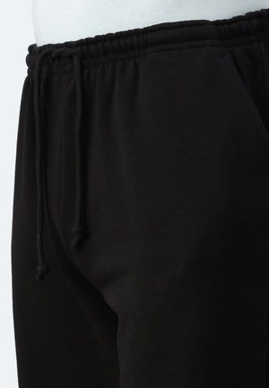 Pantaloni della tuta neri in morbido tessuto, dotati di una vita elastica con cordino e tasche laterali. Tessuto liscio con vestibilità comoda.