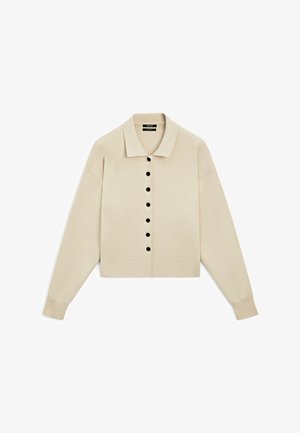 Beżowy sweter rozpinany na guziki, z kołnierzem koszulowym, czarnymi guzikami z przodu, długimi rękawami i ściągaczami przy mankietach.