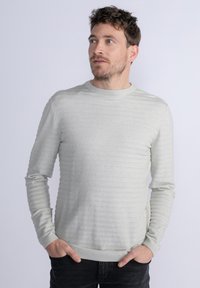 Jasnoszara dzianinowa sweter z poziomą żebrowaną teksturą, okrąg�łym dekoltem i długimi rękawami. Dopasowany krój z delikatnym rozciągnięciem.