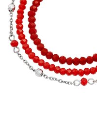 Bracciale rosso con perline composto da tre filamenti di perline sfaccettate, alternate a anelli di catena argentata e una perla di accento argentata.