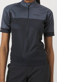 Kortärmad cykeltröja i mörkgrått, med hela dragkedjan, nättextur och en figurnära design med diskret branding på bröstet.