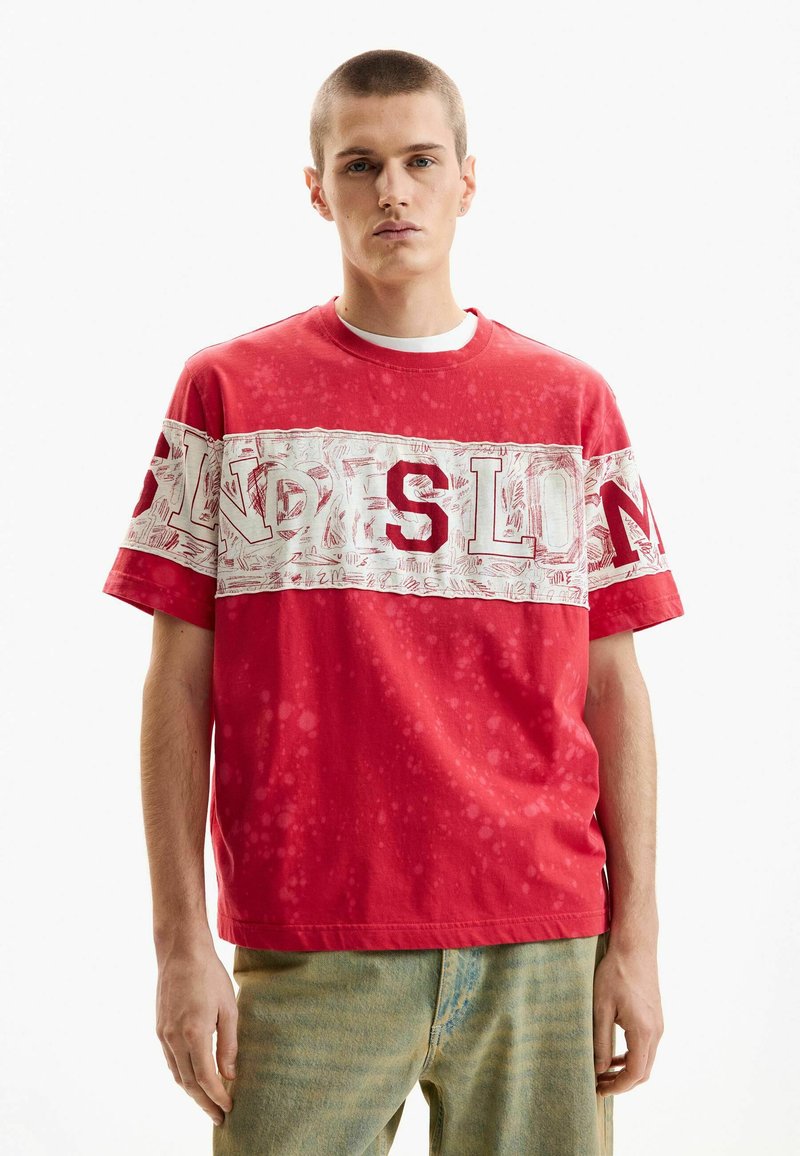 Red cotton short-sleeve t-shirt featuring a prominent white pattern across the chest with text, complemented by a relaxed fit and crew neck.