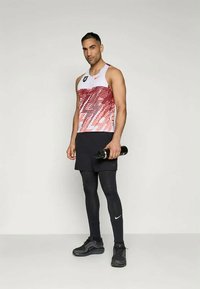 Futó felszerelés, amely tartalmaz egy ujjatlan, fehér és piros áttetsző trikót, fekete rövidnadrágot, fekete leggingset és fekete sportcipőt. Vízpalack is tartozik hozzá.