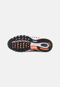 Semelle d'une chaussure de course Nike Air Pegasus blanche et orange montrant une bande de roulement noire avec des accents rectangulaires orange.