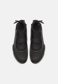 Czarne buty sportowe o gładkim matowym wykończeniu, z zapięciem na sznurówki i zaokrąglonym noskiem. Minimalistyczny styl z delikatnymi szwami.