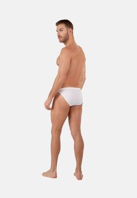 Slip bianchi in cotone mostrati su un modello maschile, con vestibilità aderente e textura liscia. Lo sfondo è semplice e discreto.