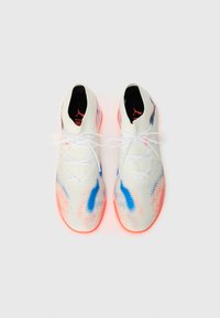 Weiße Sportschuhe mit blauen und rosa Akzenten, strukturiertem Obermaterial und leuchtend orangefarbigen Sohlen. Verfügt über ein auffälliges Schnürsystem.