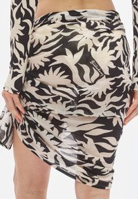 Čiernobiela zavinovacia sukňa s kvetinovým vzorom z ľahkej látky, s charakteristickou etiketu na boku.