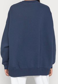 Marinblå sweatshirt med avslappnad passform, rund halsringning och sänkta axlar. Mjukt tyg med en slät yta och ribbad nederkant.