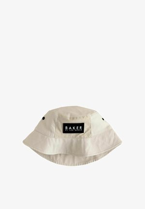 Sombrero tipo bucket beige con una parche rectangular negro en la parte frontal que dice "BAKER BY TED BAKER", con pequeños ojetes negros en los laterales.
