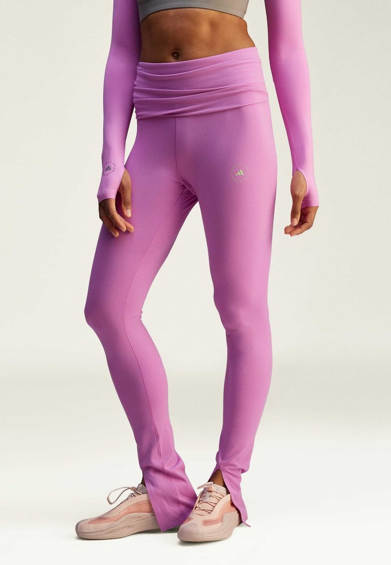 Rosa träningsleggings har en hög midja med en samlad design, elastiskt tyg och utskärningar vid anklarna. Matchande åtsittande långärmad topp.