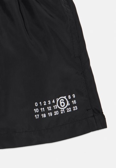 Svarta shorts i lättviktsmaterial med ett vitt tryckt kalenderdesign där nummer 6 är markerat på nederkanten.