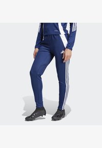 Blaue sportliche Jogginghosen aus glattem Stoff, mit weißen Seitenstreifen und einem Adidas-Logo auf dem linken Oberschenkel.