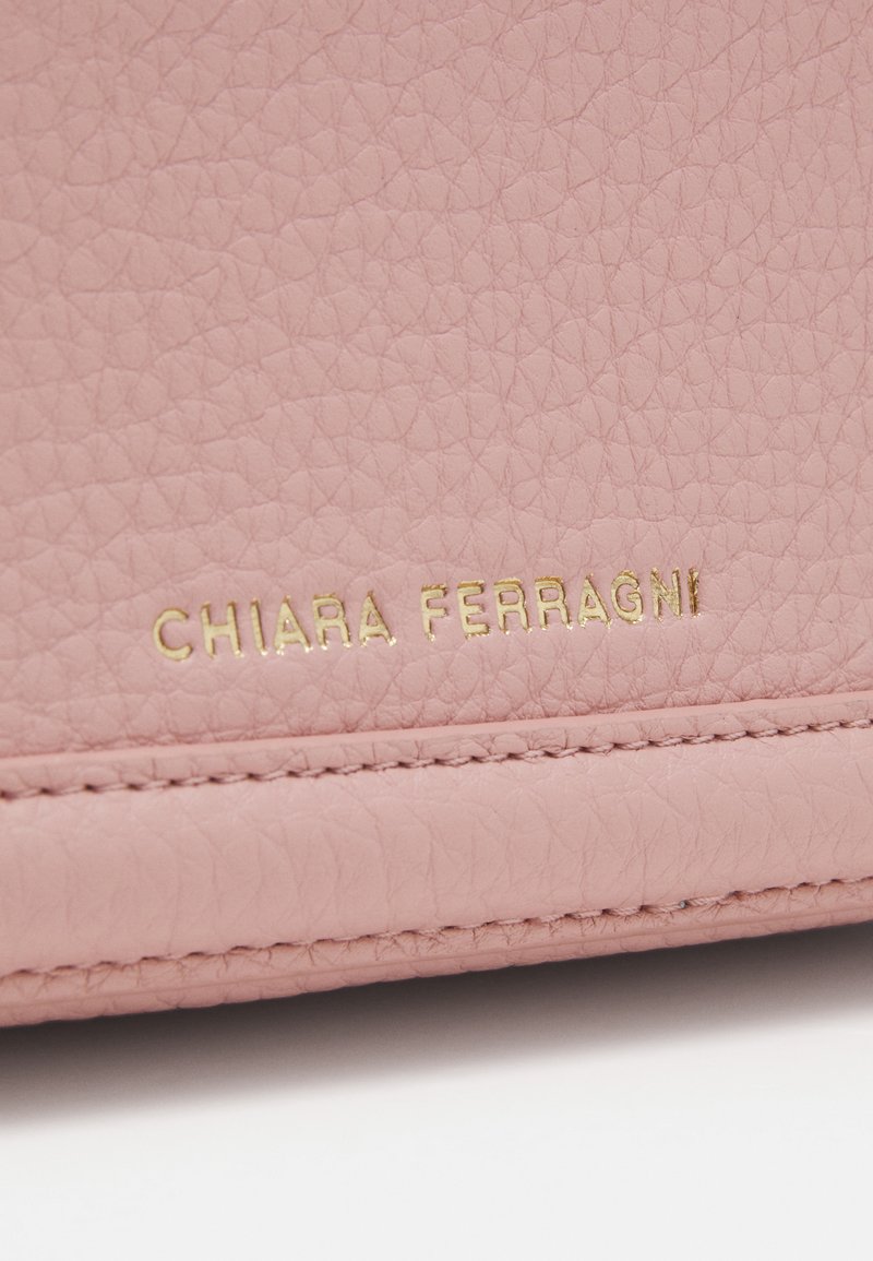 Portafoglio in pelle rosa chiaro con superficie texture e logo dorato "CHIARA FERRAGNI." Presenta cuciture lungo il bordo.