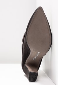 Scarpa nera in suede con tacco alto, punta affusolata e suola testurizzata, con logo argentato e taglia 37 indicata all'interno.