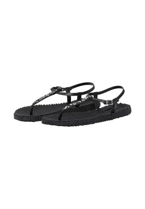 Sorte flettede flade sandaler med T-remdesign, justerbar ankelspænde og dekorative rhinsten på de forreste remme.