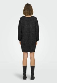 Robe pull noire à manches longues, col rond et coupe décontractée. Fabriquée en tissu tricoté texturé, se terminant au-dessus du genou.