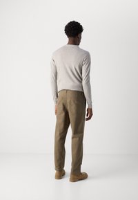 Lysegrå langærmet trøje parret med khaki bukser og beige sko. Bukserne har to baglommer og en afslappet pasform.