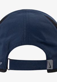 Kék sapka ívelt peremmel, hálós panelekkel és nejlon pánttal. A hátsó részén egy szürke Nike logó található, valamint látható varrási részletek.