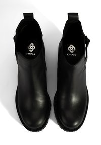 Bottines en cuir noir avec finition lisse, dotées d'un dos surélevé, de panneaux latéraux élastiques et de semelles en caoutchouc texturé. Marque visible à l'intérieur.