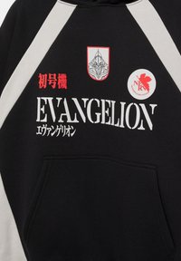 Sort-hvid hættetrøje med teksten "EVANGELION", røde japanske tegn, et robot-hovedemblem og en rød cirkulær NERV-logo på brystet.