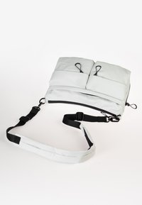 Helle graue, gepolsterte Schultertasche mit zwei Außentaschen, verstellbarem schwarzen Riemen und Schlaufen-Hardware-Details für zusätzliche Trageoptionen.