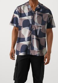 Lyhythihainen napillinen paita, joka on valmistettu kevyestä kankaasta ja jossa on abstrakti kuosi navy, kerma- ja taupe-sävyissä.