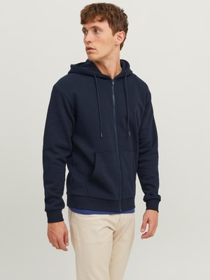 Marinefarvet zip-up hoodie lavet af blødt stof, med en frontlomme, snoretræk i huen og ribbede manchetter. Bæres med lyse farvede bukser.