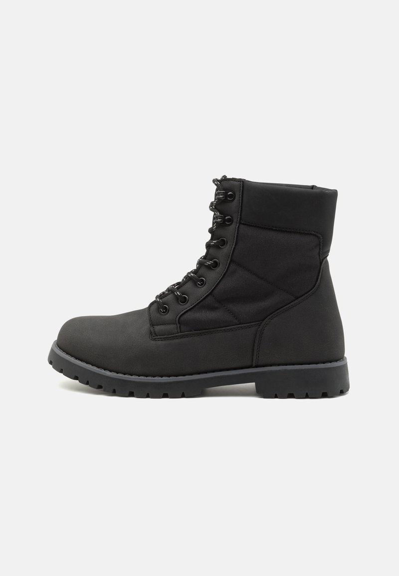 Bottine noire à lacets avec col rembourré, semelle robuste et coutures renforcées, présentée de profil sur fond blanc.