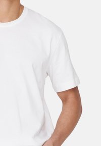 Weißes Baumwoll-T-Shirt mit kurzen Ärmeln und Rundhalsausschnitt. Glatte Textur, schlichtes Design, keine Muster oder Akzente. Lässige Passform.