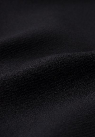 Țesătură neagră cu o suprafață moale și texturată, având pliuri subtile și un aspect uniform, indicând un material neted și cald.