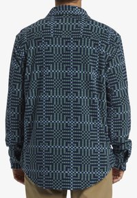 Flanellen overhemd met een donkerblauw en groen geometrisch patroon, lange mouwen, een kraag en een gebogen zoom. Soepele, zachte textuur.