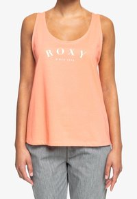 Top sin mangas de color coral claro, hecho de algodón suave, con un escote redondo y el texto "ROXY" acompañado de "desde 1990" impreso en blanco.
