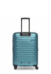 Maleta rígida en color teal, con surcos verticales, un mango telescópico y cuatro ruedas para mayor movilidad. Superficie texturizada para mayor durabilidad.