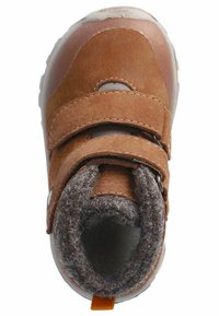 Botín de ante marrón con doble tira de Velcro, forro gris y un puño de tobillo texturizado. Presenta una suela de goma blanca y una pestaña en el talón de color naranja.