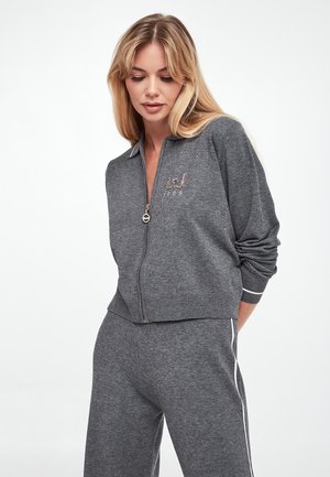 Giacca grigia con zip, dotata di polsini e orlo a coste, caratterizzata da un logo minimalista decorato con paillettes. Realizzata in un morbido tessuto con una vestibilità sportiva.