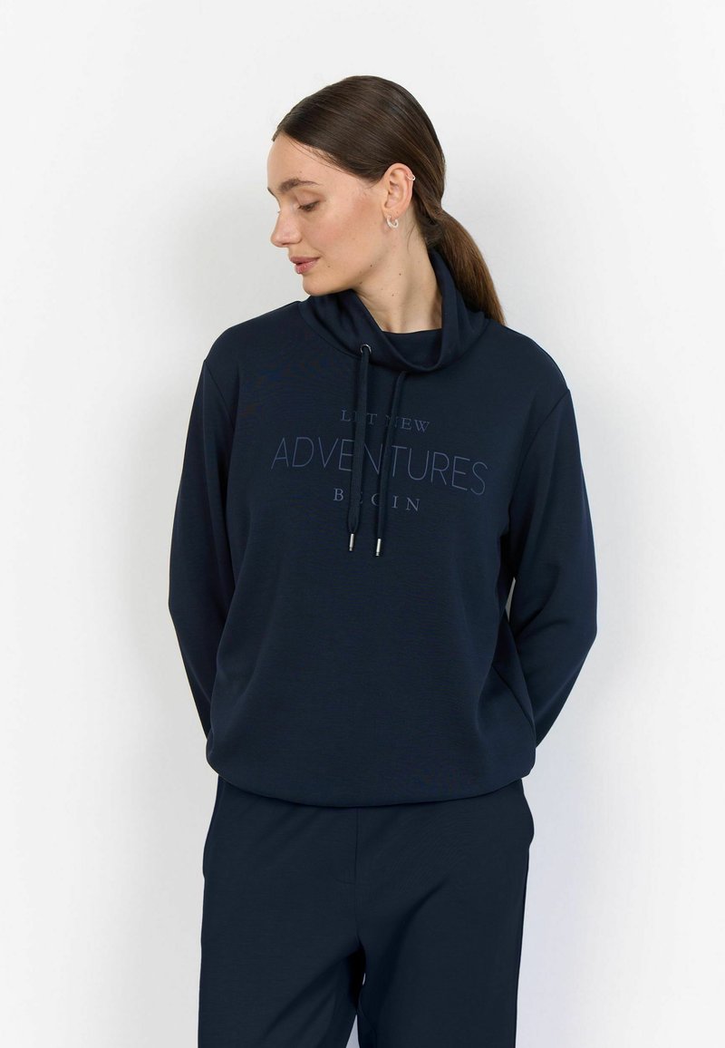 Felpa blu navy con collo a imbuto e cordino, caratterizzata da un testo stampato "ADVENTURES" sul davanti, abbinata a pantaloni coordinati.